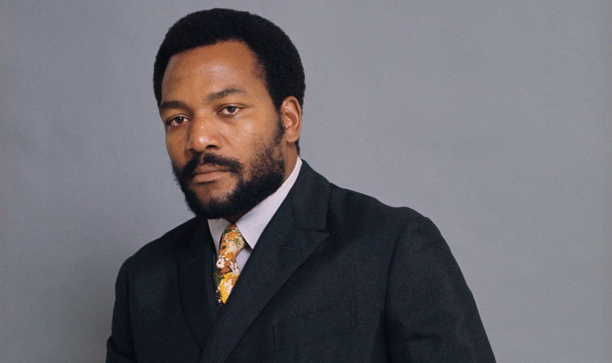 Athlete and Actor Jim Brown Standing Behind Chair