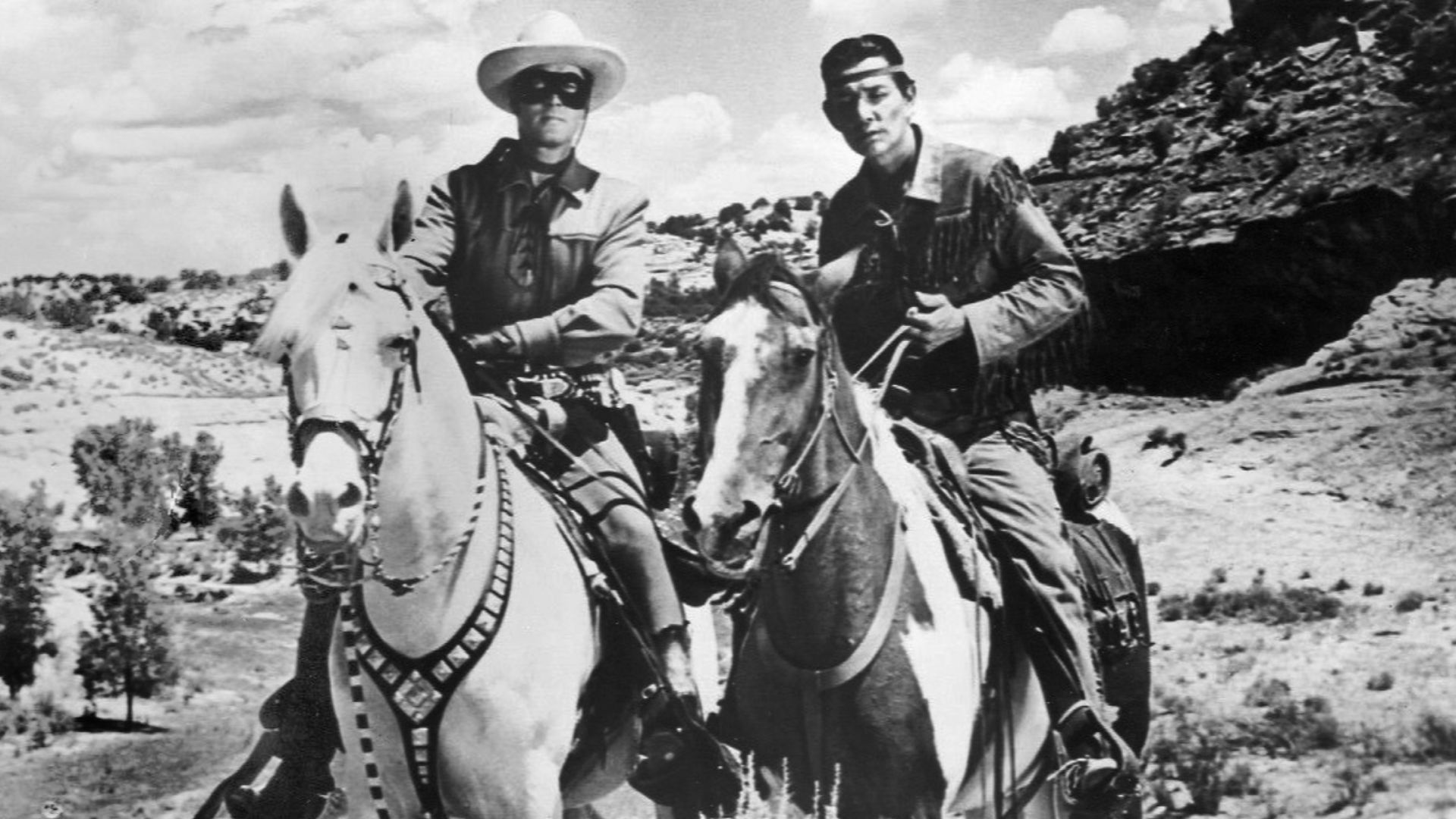 Photo of Clayton Moore as the Lone Ranger and Jay Silverheels as Tonto.  Moore is riding Silver, while Silverheels is riding Scout.