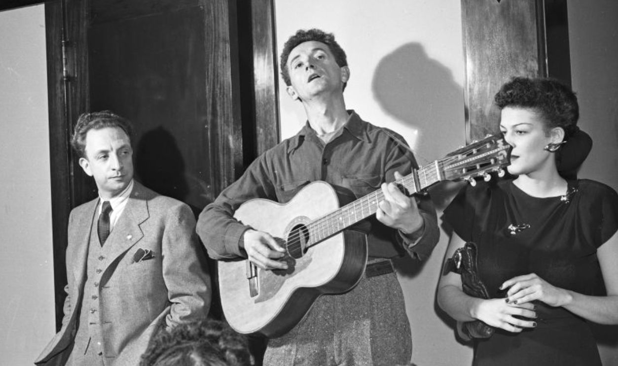 Musician Woody Guthrie plays guitar - 1940
