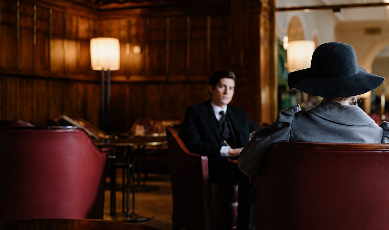A man and woman in formal attire having a conversation in a stylish restaurant setting