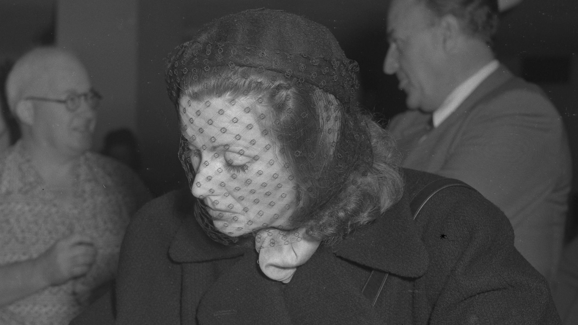 Actress Greta Garbo filling out paperwork for United States citizenship  wearing a veil