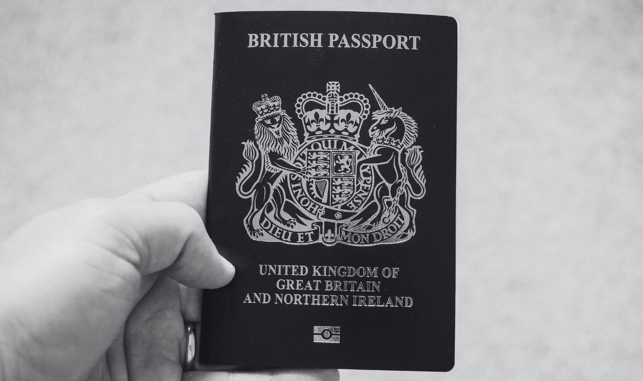 Close-up of a hand holding a British passport, symbolizing citizenship and travel