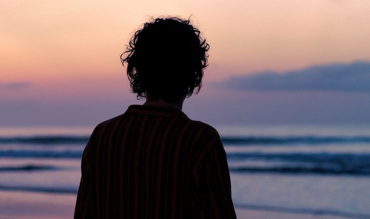 Silhouette of a person on Takoradi beach at sunrise with vibrant sky colors