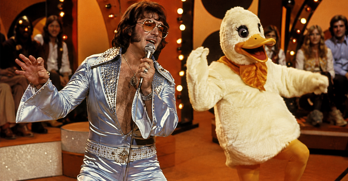 1970s singer on stage with a duck mascot dancing nearby