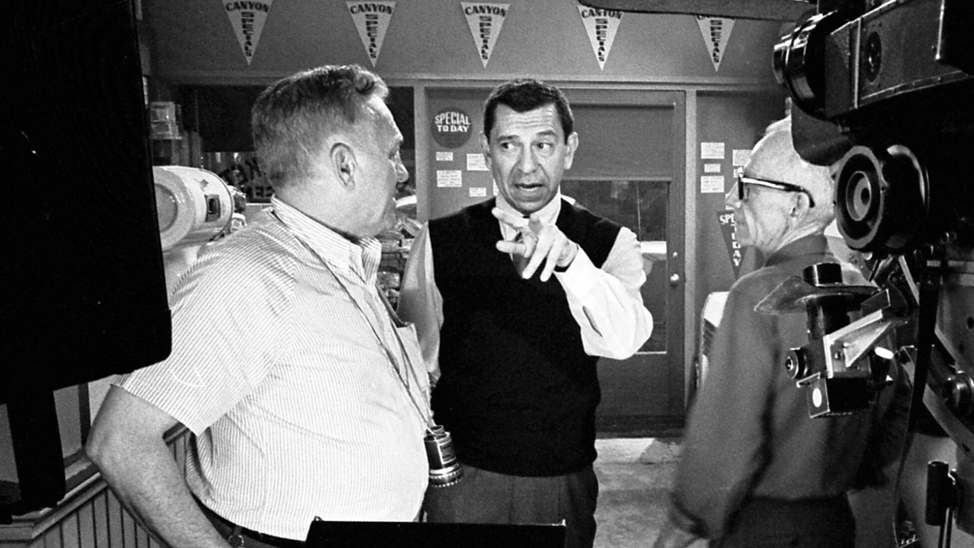 Jack Webb, center, confers with cinematographer Walter Strenge, left, and crewman Ray Bensfield on set of Dragnet 1966.