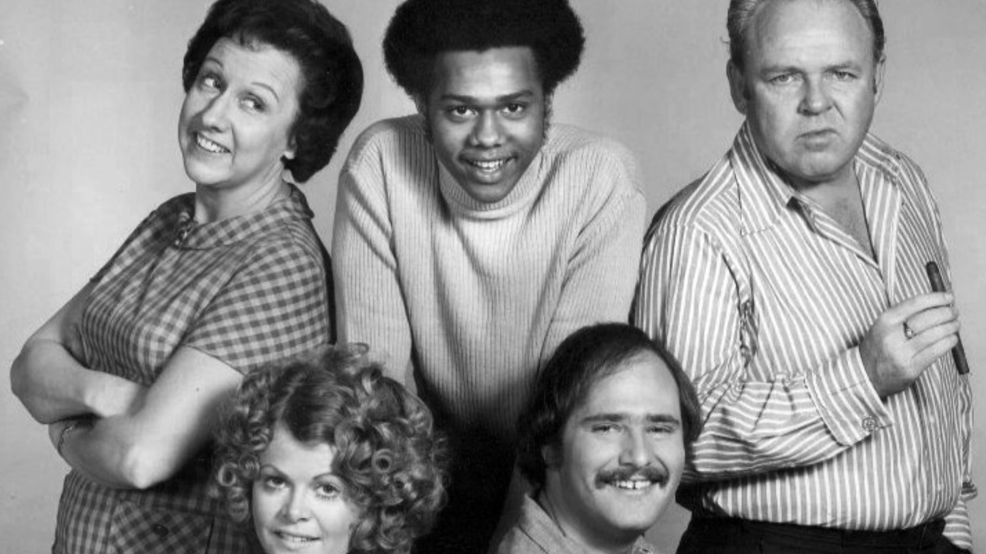 Photo of the cast of the television program All In the Family.  Standing, from left: Jean Stapleton (Edith Bunker), Mike Evans (Lionel Jefferson), Carroll O'Connor (Archie Bunker).  Seated: Sally Struthers (Gloria Bunker Stivic) and Rob Reiner (Mike Stivi