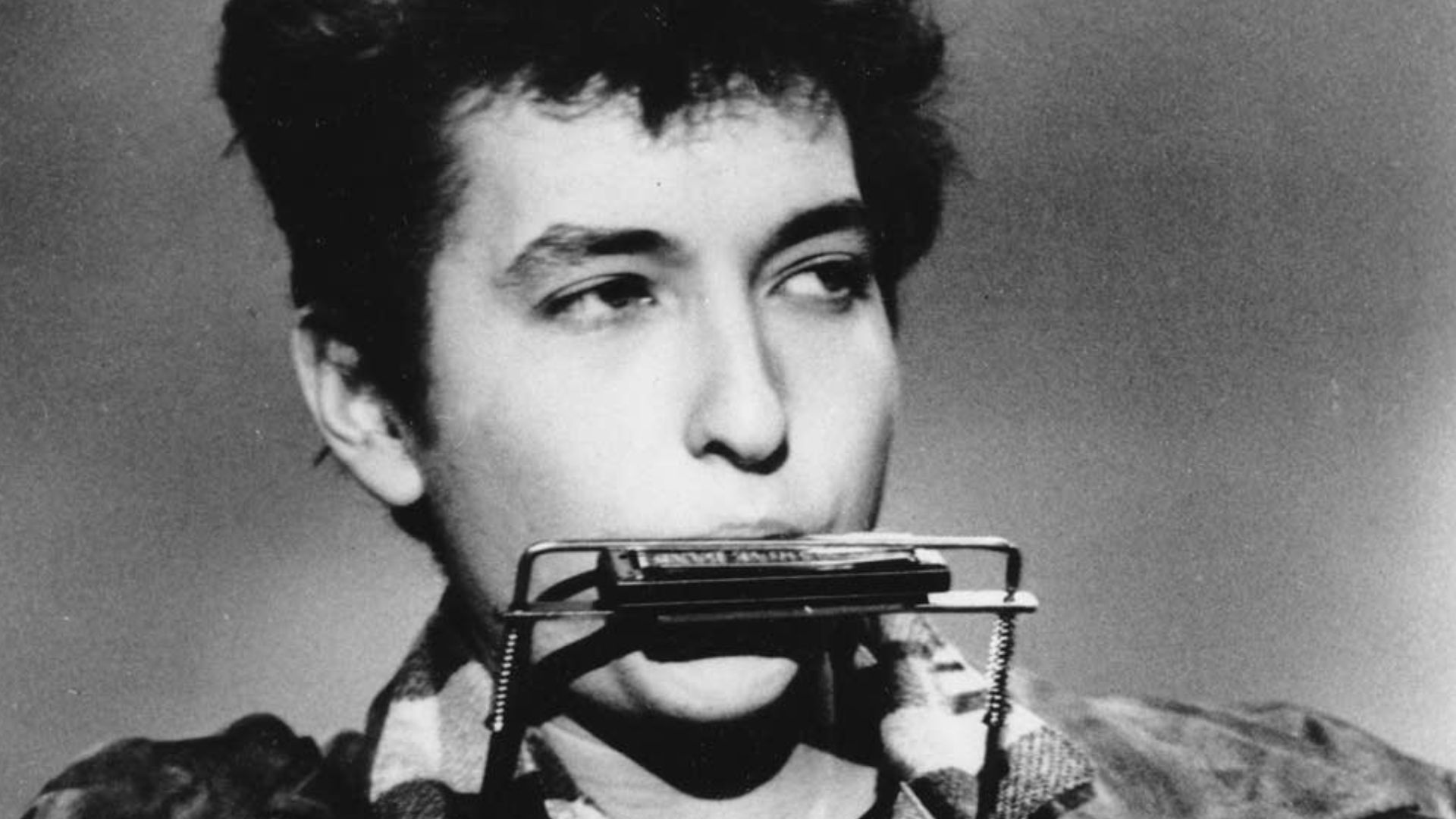 Bob Dylan plays harmonica and guitar in March 1963.
