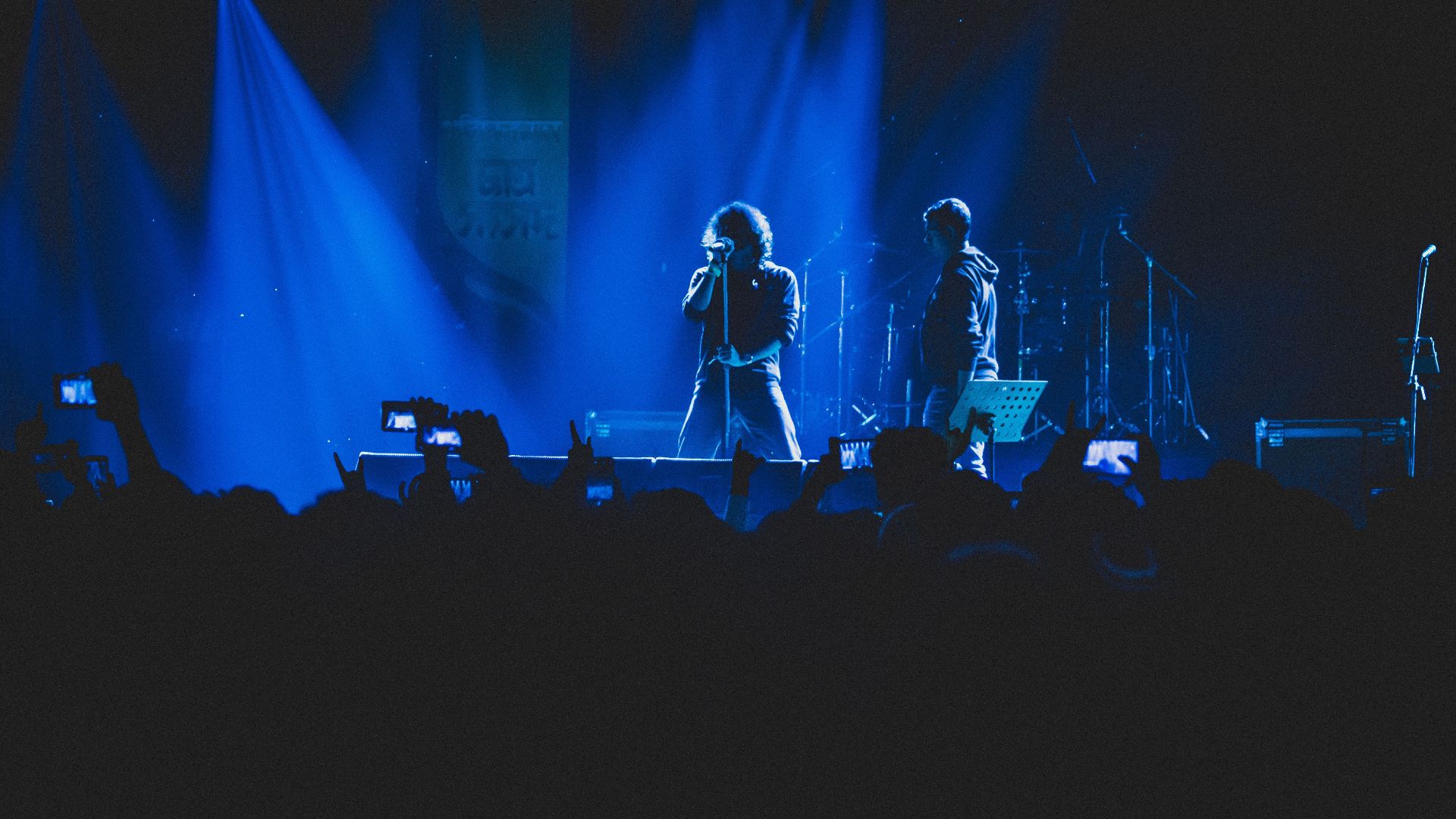 A lively concert scene with vivid lighting, featuring a singer and band on stage.