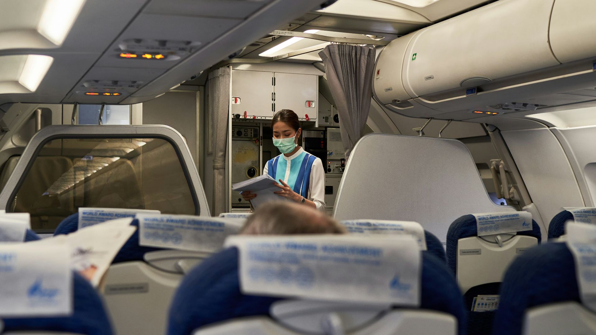 a woman in a face mask sitting on an airplane
