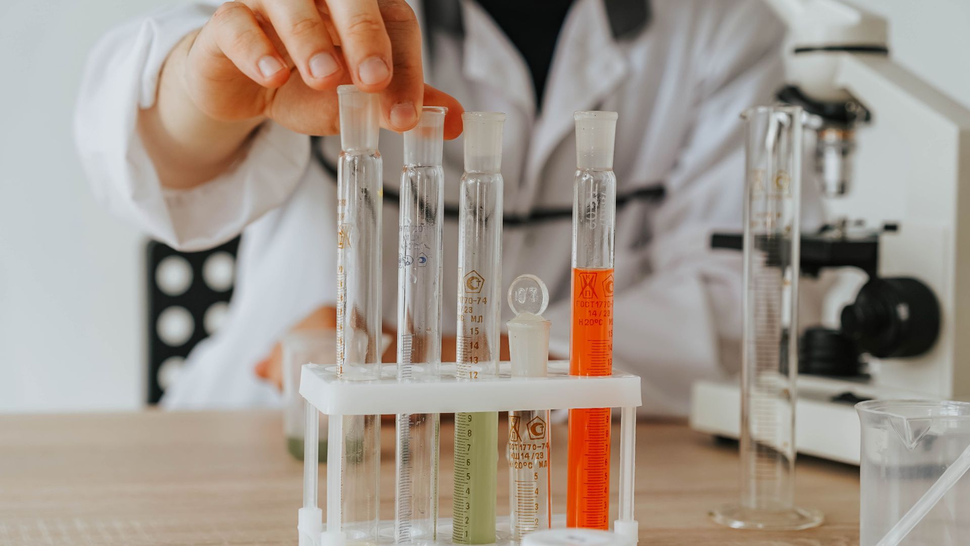 Scientist in lab coat conducting an experiment with test tubes and a microscope.