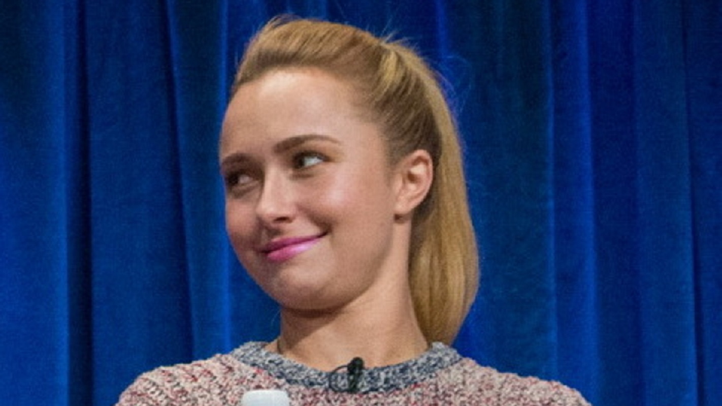Hayden Panettiere in sweater and pink lipstik looking at side and smiling at blue background - 2013