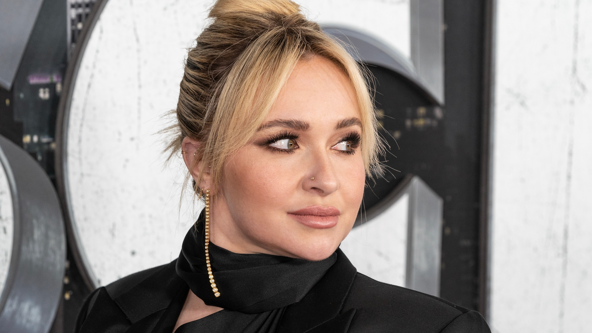 Hayden Panettiere wearing black dress and golden earrings looking at side - 2023