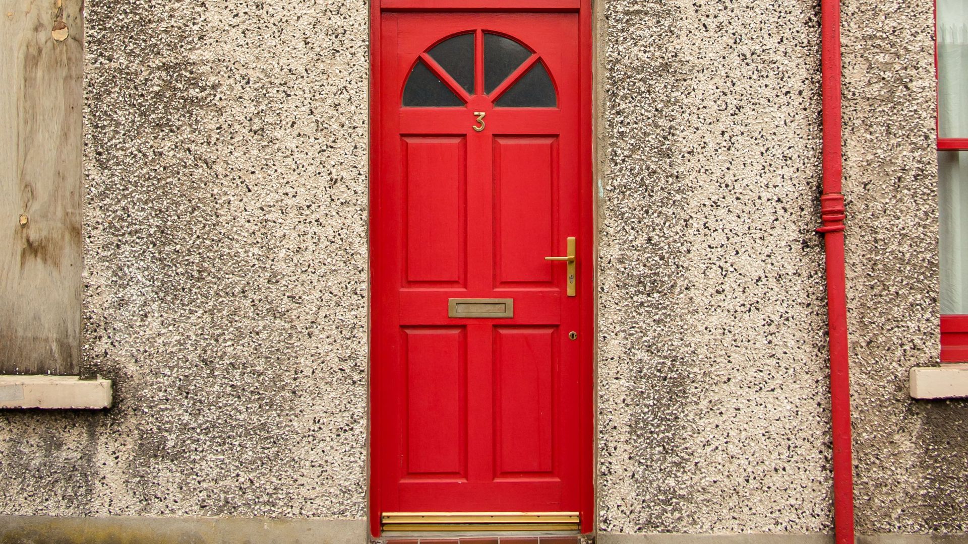 A vibrant red door on a textured wall in Londonderry, showcasing classic Irish architecture.