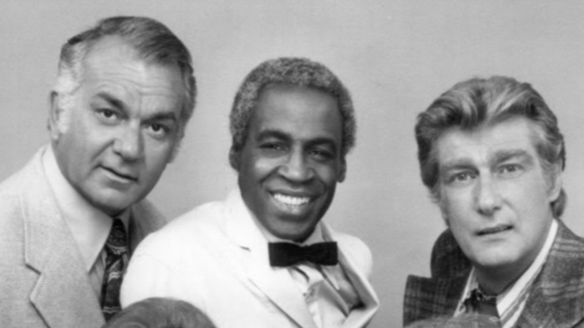 Photo of the Campbells and Tates with Benson from the television program Soap.  Standing, from left: Robert Mandan (Chester Campbell), Robert Guillaume (Benson), Richard Mulligan (Bert Campbell).  Seated, from left: Katherine Helmond (Jessica Tate), Cathr
