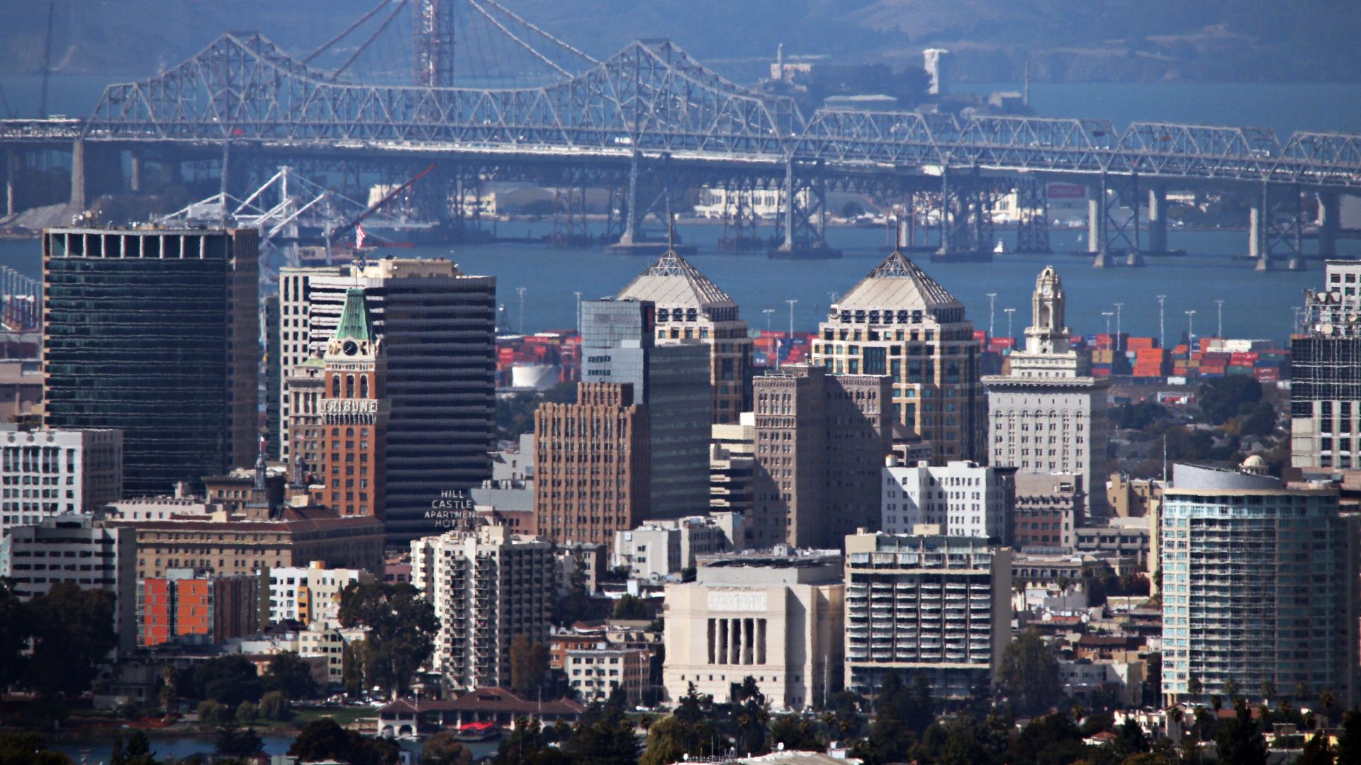 The Oakland skyline as seen from the Oakland hills. Oakland, CA has a population of about 400,000 and functions as the principal port city of Northern California. Both the old and new eastern span of the San Francisco-Oakland Bay Bridge can be seen in the