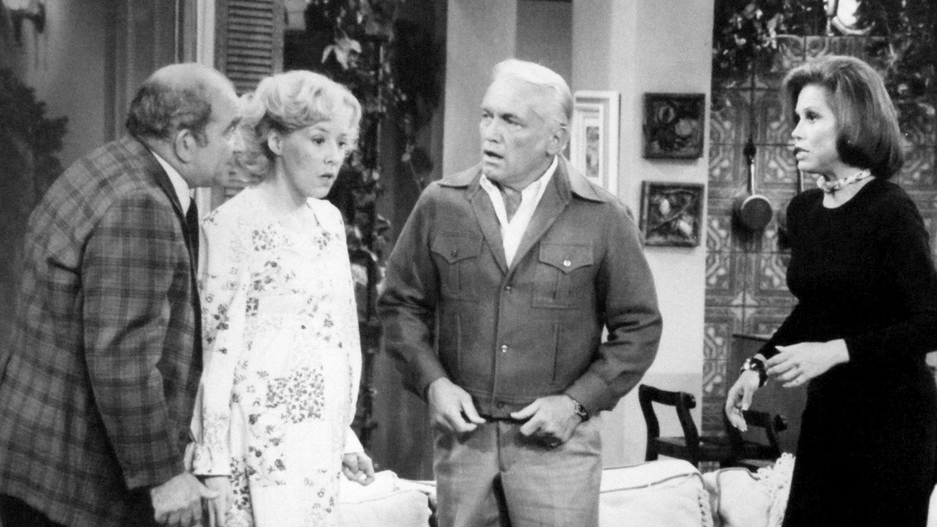 Photo from The Mary Tyler Moore Show.  Mary gives a dinner party that winds up as a birthday party when Georgette Baxter goes into labor during the dinner.  From left: Ed Asner (Lou Grant), Georgia Engel (Georgette Baxter), Ted Knight (Ted Baxter) and Mar