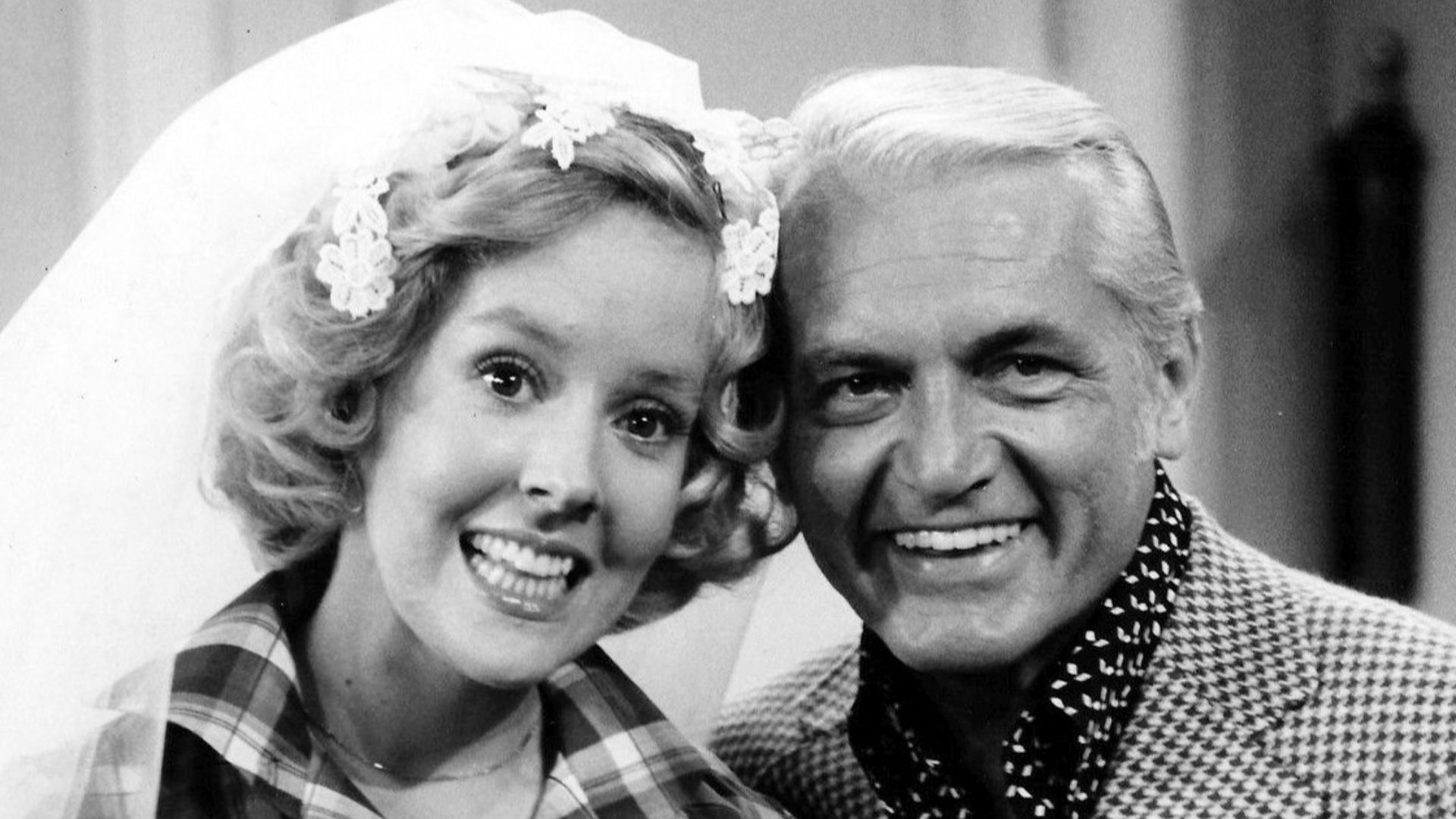 Photo of Georgia Engel and Ted Knight from the television program The Mary Tyler Moore Show.  Georgette Franklin (Engel) and anchorman Ted Baxter (Knight) have just been married at an impromptu ceremony at Mary Richard's (Tyler Moore) apartment.