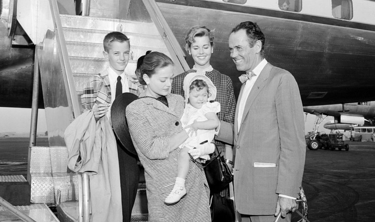 (Original Caption) Fonda Family Flies Away. Queens, New York, New York: Actor Henry Fonda and his family are posing smilingly here before boarding a Lai-Italian Airlines plane at Idlewild Airport to fly to Rome. Mrs. Fonda holds infant daughter Amy while son Peter and daughter Jane Bean in background. Fonda is scheduled to start work on his new picture, War and Peace, in the eternal city.