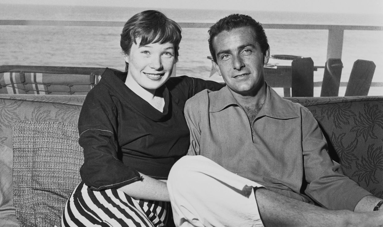 American actress and singer Shirley MacLaine, wearing a black sweater and striped trousers, and her husband, American businessman and film producer Steve Parker (1922-2001), in a shirt and white trousers, relaxing at their beach front home, in Los Angeles, California, 28th March 1955.