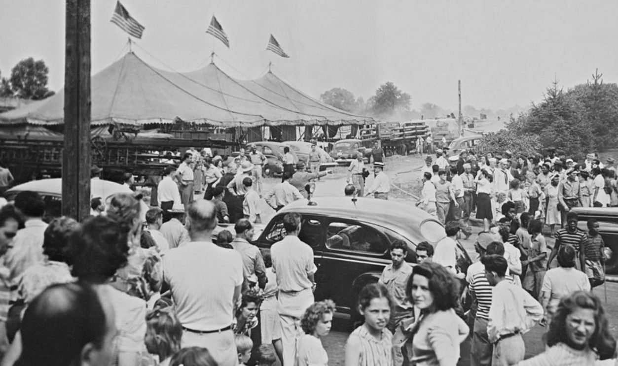 Survivors watch as smoke rises from the the big main tent of the Ringling Brothers and Barnum and Bailey Circus, in Hartford, Connecticut, which went up in flames causing the deaths of 127 people with many more injured. At left is the menagerie tent which escaped destruction.