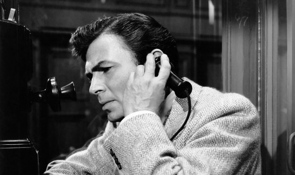 British actor James Mason (1909 - 1984) uses a phone booth in a scene from the Columbia Pictures film 'The Blank Wall', later titled 'The Reckless Moment', 1949.