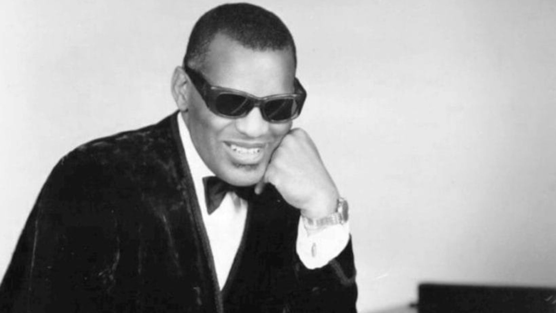 Photo of Ray Charles in one of his classic poses at the piano.