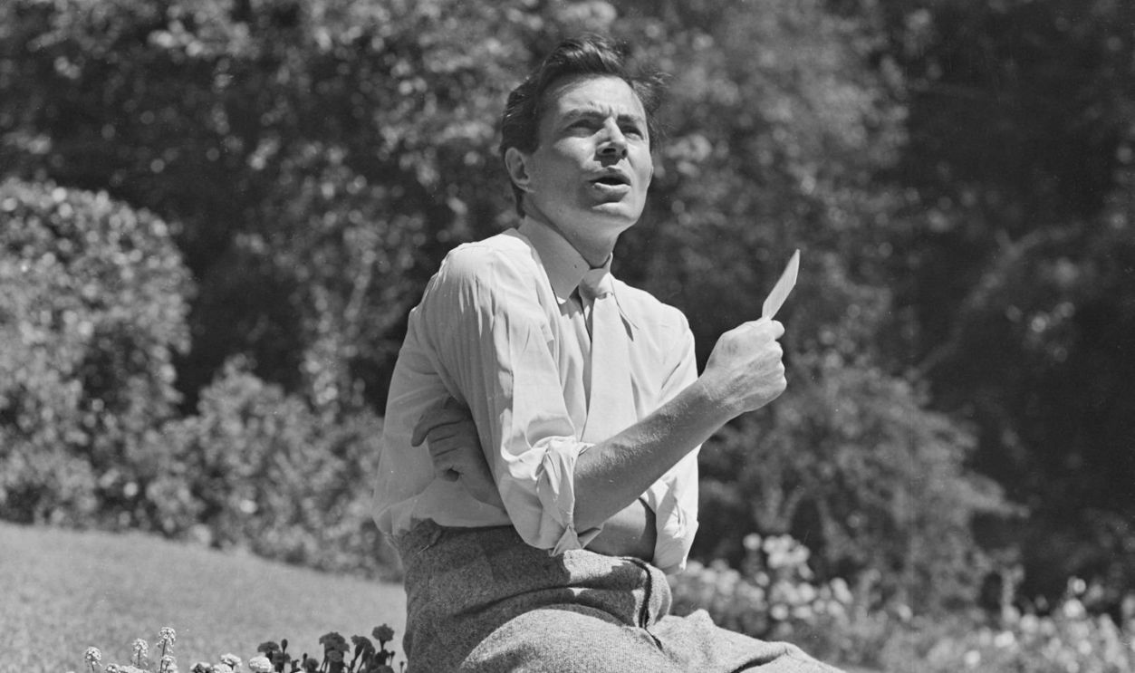 English actor James Mason (1909 - 1984) perches on a wall, USA, circa 1950.