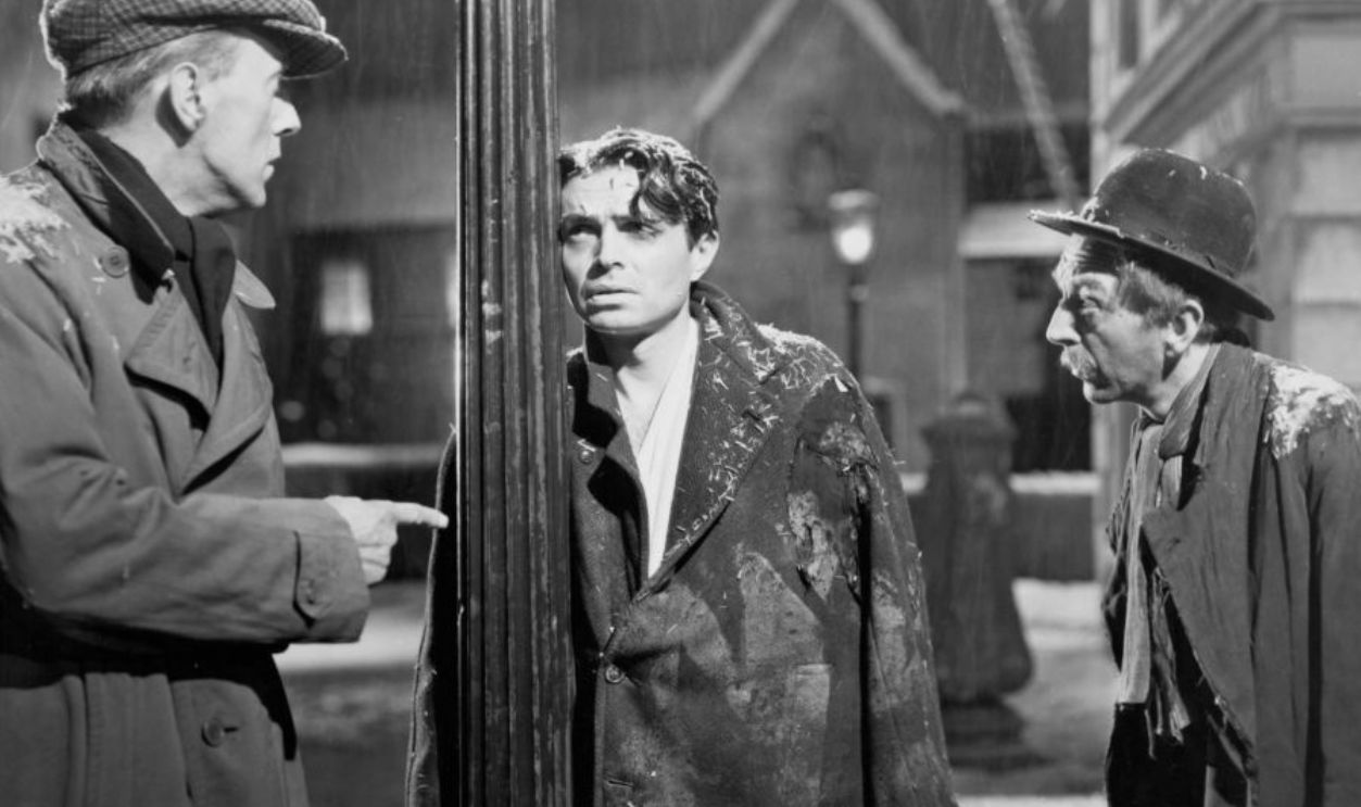 James Mason talks with two old men in a scene from the film 'Odd Man Out', 1947.