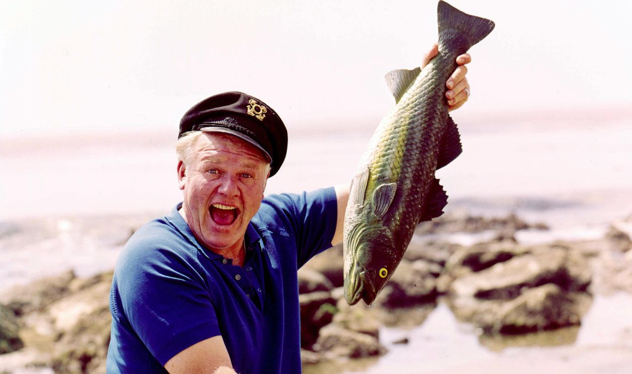 Getty Images - 119060879 - Alan Hale Jr (1921-1990), US actor, sitting on a rock while holding up a fish in a publicity portrait for the television series 'Gilligan's Island', in which Hale Jr played 'The Skipper', USA.