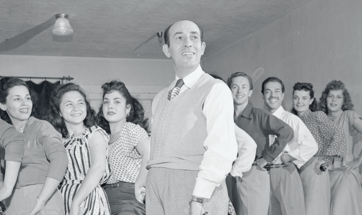 Rita's Dad Teaches Dancing. Los Angeles: Teaching dancing to a class in his Los Angeles studio is Eduardo Cansino, father of screen star Rita Hayworth. Rita will marry the wealthy Moslem prince, Aly Khan, in Vallauris, southern France, about May 27.