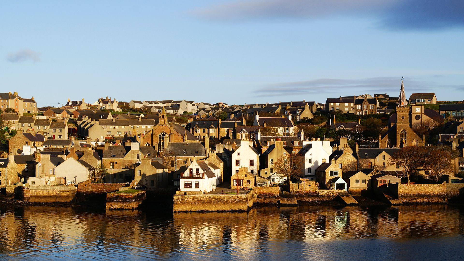 The town of Stromness, Orkney Islands, Scotland, UK. The two church buildings are clearly visible. The one with the spire in the right is the former North Church converted into a Town Hall.