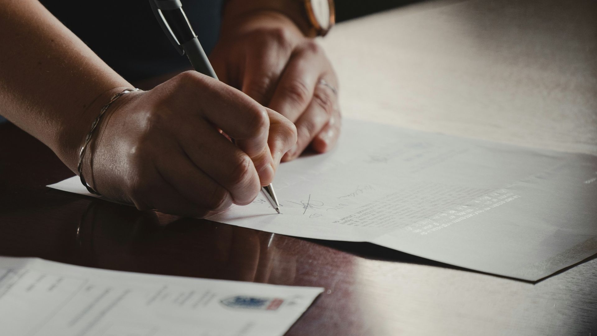 person in orange long sleeve shirt writing on white paper