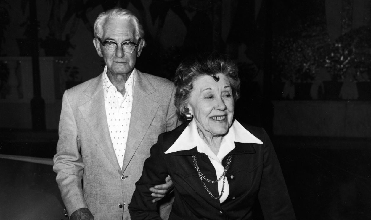American power company manager Homer Carson (1899 - 1983) and wife Ruth Carson (1901 - 1985), the parents of American talk show host and comedian Johnny Carson, walk arm-in-arm between parked cars in Hollywood, California, October 1974.