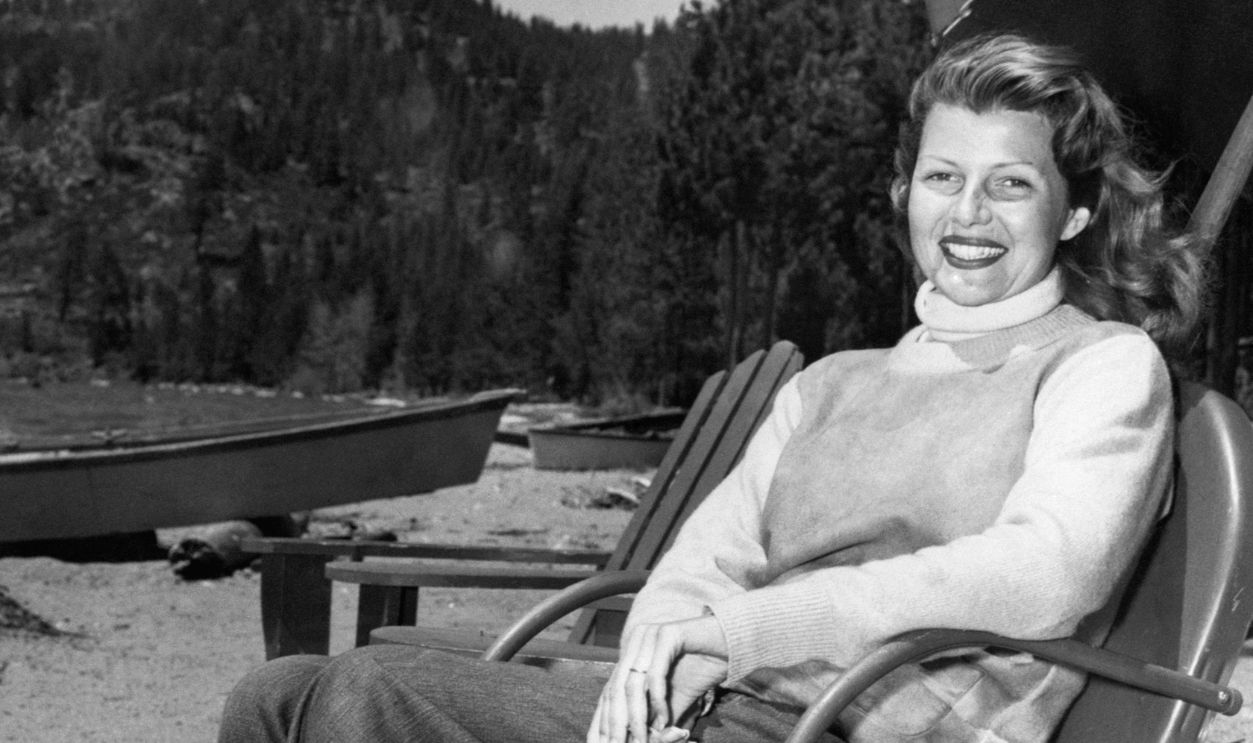 Rita Hayworth sitting on a lawn chair at her lakefront home in Glenbrook, Nevada