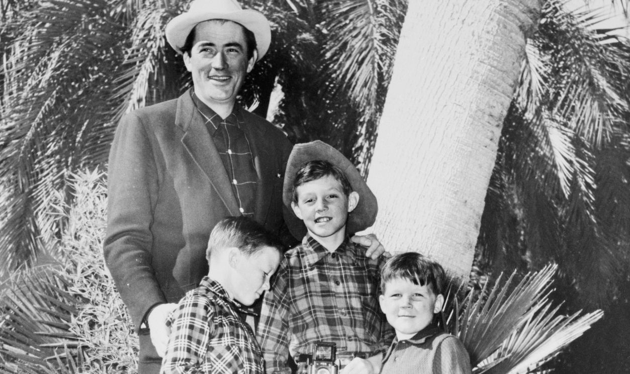 The cowboy flavor is strong as Gregory Peck and his three sons gather for a family photo after a visit to the rodeo at Palm Springs.
