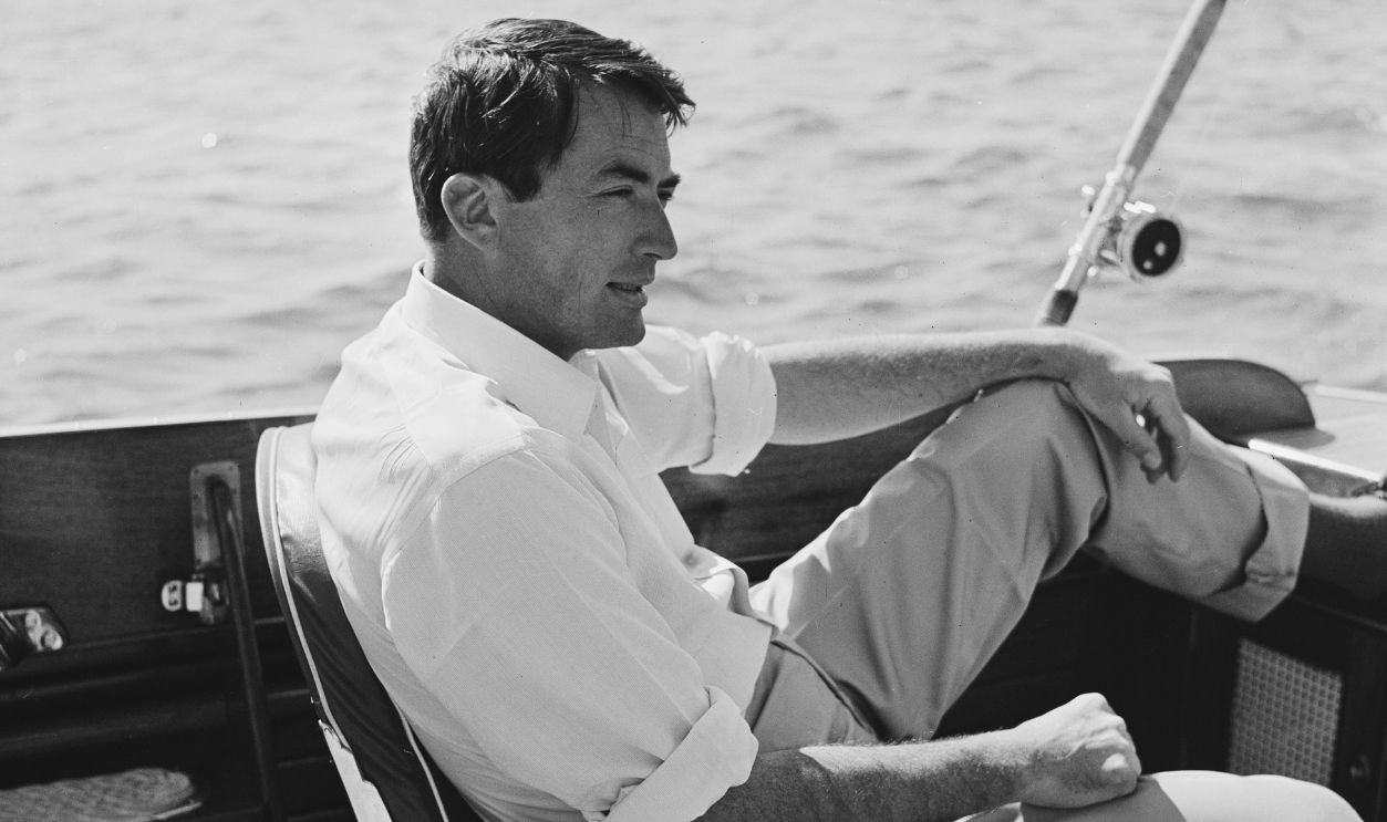 American actor Gregory Peck (1916-2003) sits in a deep sea fishing chair and waits for the rented 35-foot vessel to arrive at the fishing grounds, at sea, 28th June 1956.