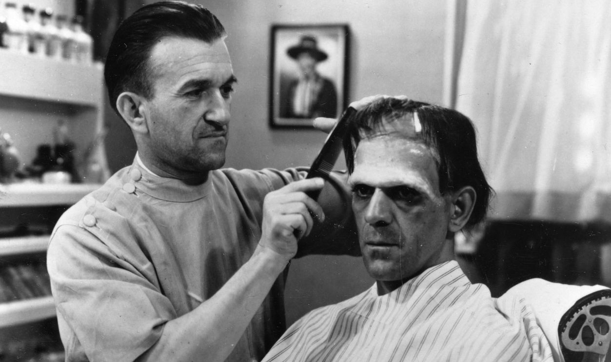Greek-born American make-up artist Jack P. Pierce (born Janus Piccoulas, 1889 - 1968) (left) applies make-up and combs the hair of British actor Boris Karloff (1887 - 1979) for Karloff's role as the monster in the James Whale-directed film 'Frankenstein,' California, 1931.