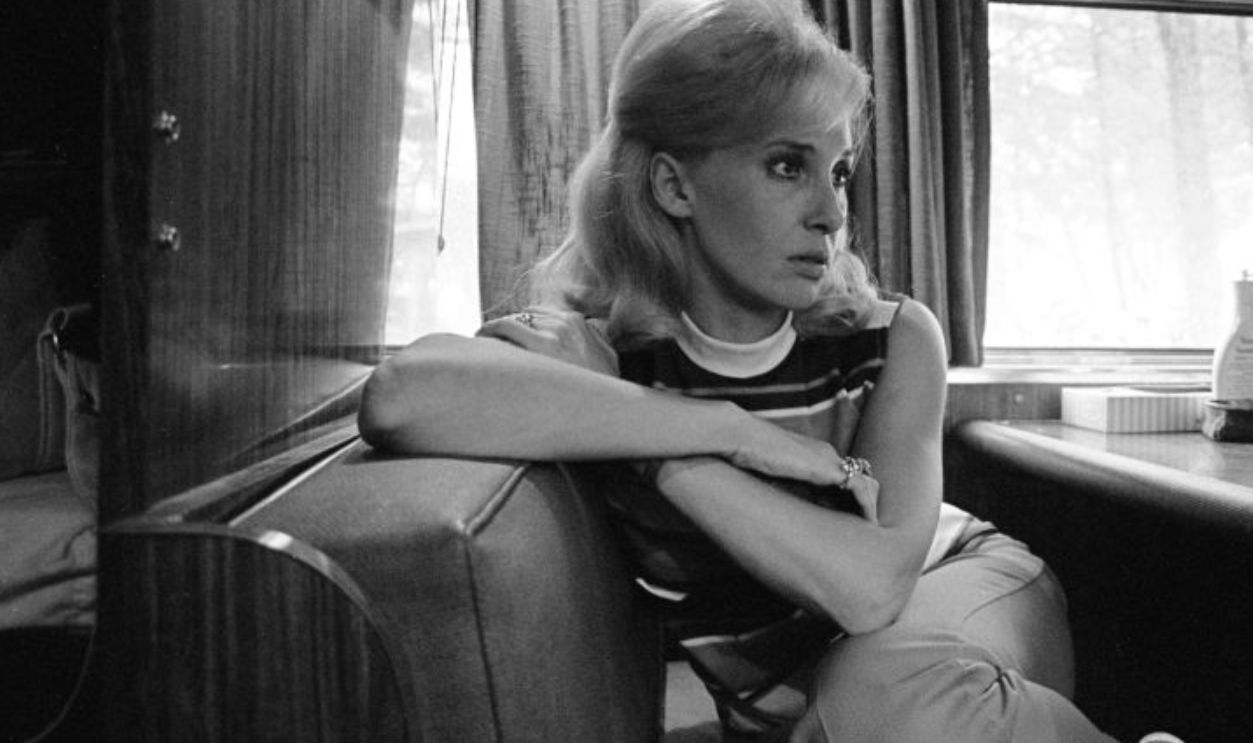 Country music performer and recording artist, Tammy Wynette sitting on her tour bus wearing a sleeveless striped shirt and Capri style pants. Shot full frame in Lavonia, Georgia 1971. Photo is part of the Nashville Music Collection.