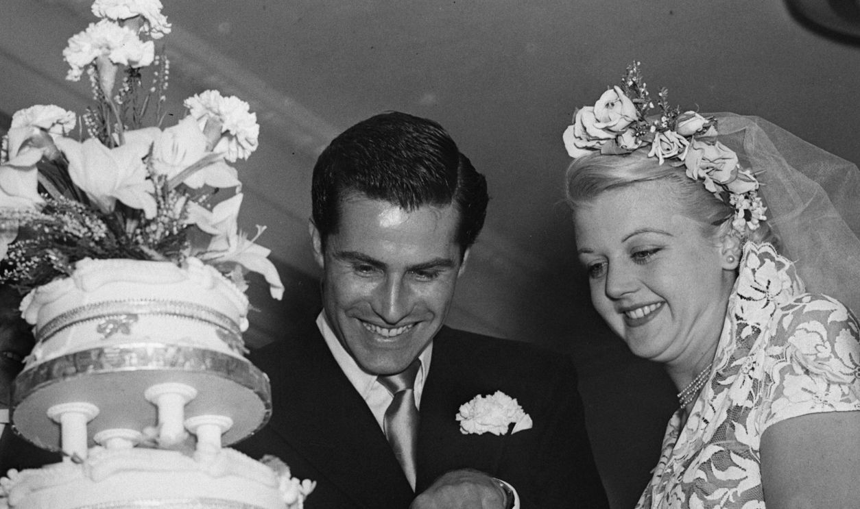 British actress Angela Lansbury and her husband, Peter Shaw, cutting the cake at their wedding.