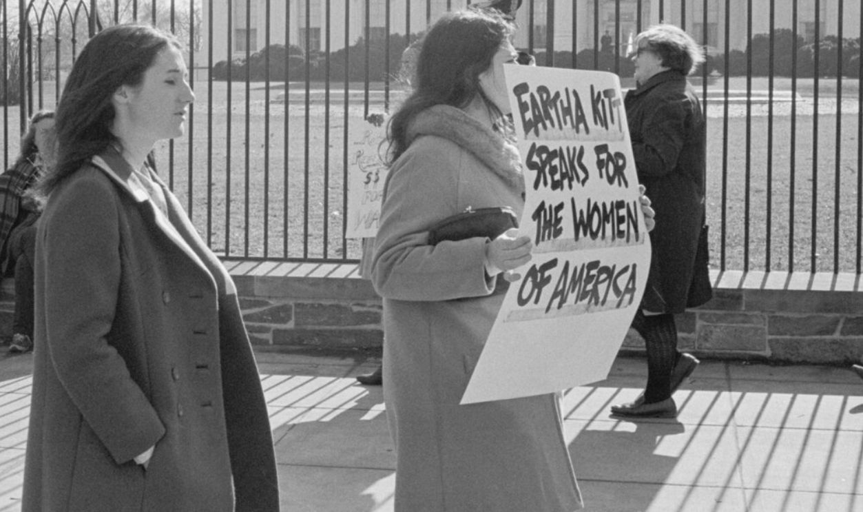 Photograph shows anti-war demonstrators carrying signs, "No more...Stop the war!", "Eartha Kitt speaks for the women of America", and "Stop the draft", picketing in front of the White House. 