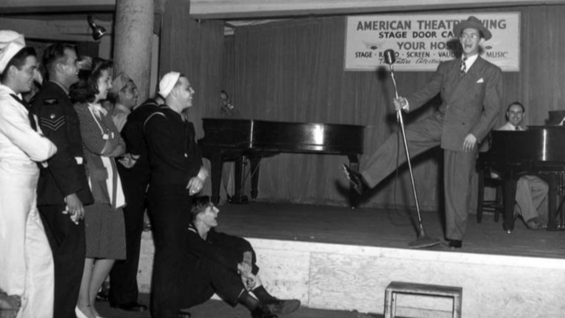 Comedian on stage, entertaining service members at the Stage Door Canteen in New York CityBroadway entertainment for the armed forces of all nations at the Stage Door canteen, run by the American Theater wing. Actors wait on soldiers and sailors who eat a