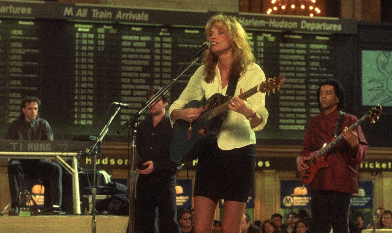 American Pop and Folk musician Carly Simon (center, in white) performs, with her band, on stage at Grand Central Station, New York, New York, April 2, 1995. Among those pictured are Tesse Gohl (left), on keyboards, Jimmy Ryan (second left), on guitar, and Doug Wimbish (right), on bas.