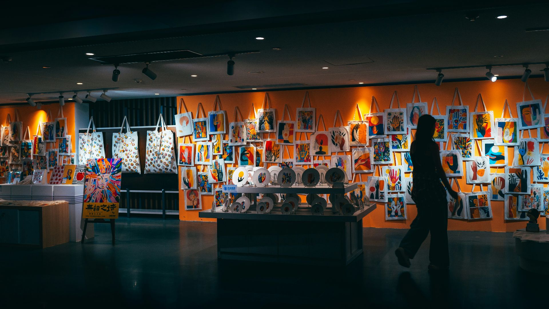 A person walks past an orange wall filled with artwork