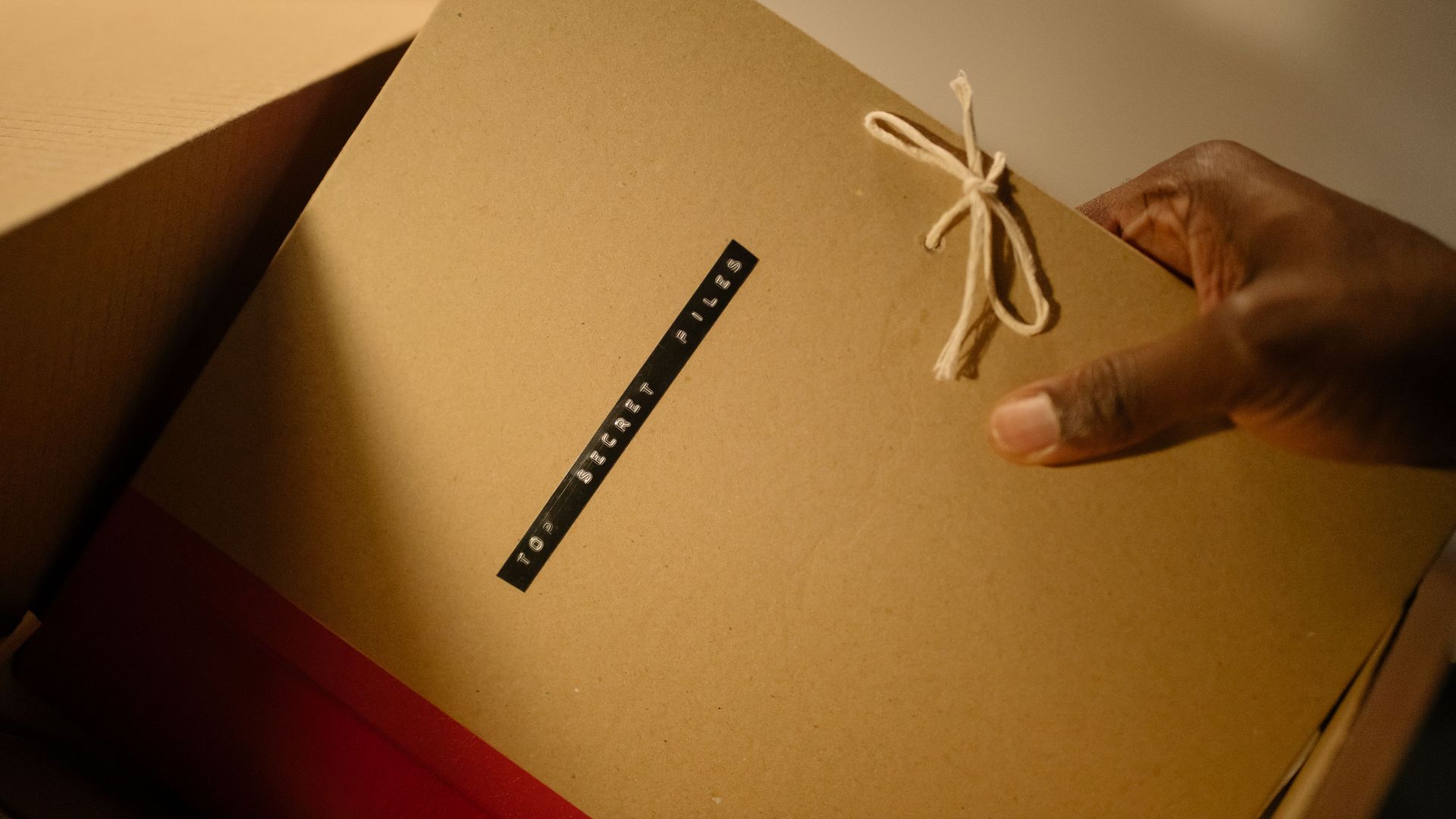 Close-up of hand holding top secret document folder in a box.
