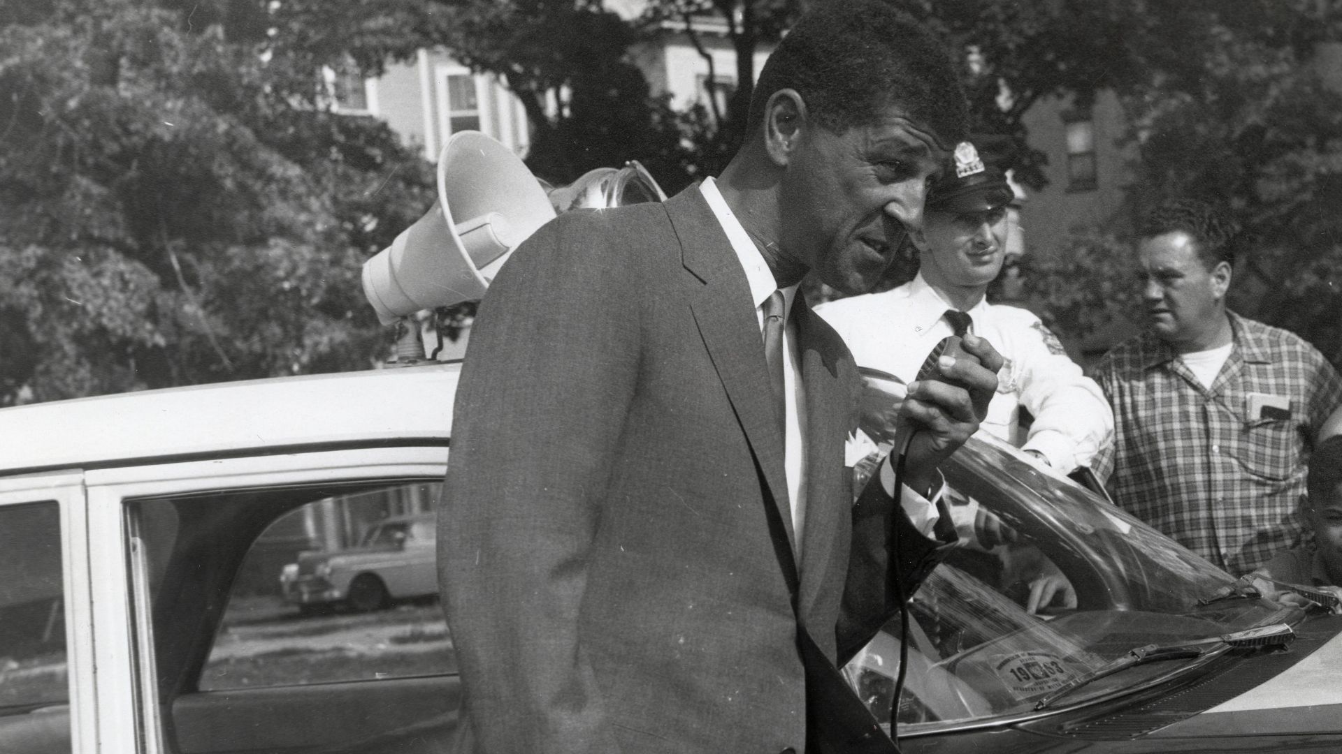 Title: Roxbury District Court Judge Elwood S. McKenney speaks through a police cruiser's PA system
Creator: City of Boston
Date: circa 1960-1968
Source: Mayor John F. Collins records, Collection #0244.001
File name: 244001_1129
Rights: Copyright City of B