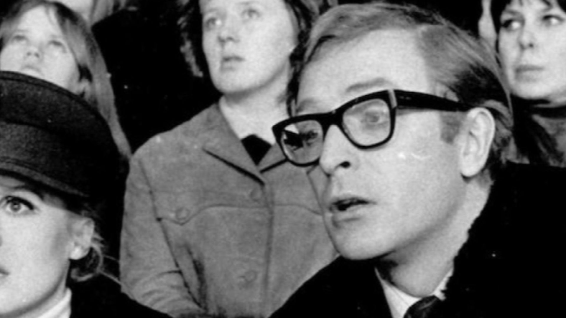 Photograph of actors Françoise Dorleac and Michael Caine watching ice hockey during the cinematography of Billion Dollar Brain in Helsinki Ice Hall.  Republished in Hufvudstadsbladet, 25 January, 2016, Varför läser Michael Caine Husis?