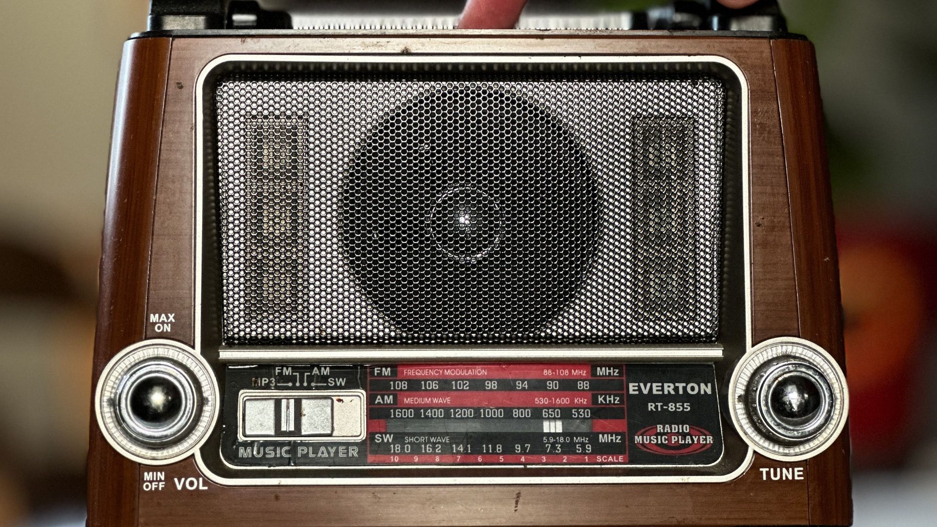 A vintage radio being tuned by a hand, evoking nostalgia in a cozy home setting.