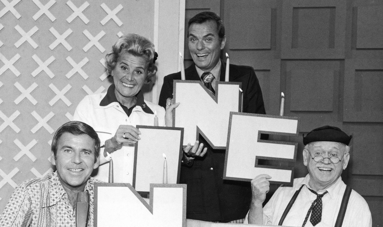 Promotional image of the celebrity panel and host from the television game show, 'Hollywood Squares' celebrating the beginning of the show's ninth season, 1974. From left to right: Paul Lynde, Rose Marie, host Peter Marshall and Charley Weaver.