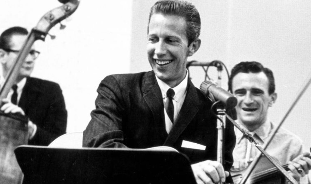 CIRCA 1963: Country singer Porter Wagoner records vocals and acoustic guitar in the studio with his upright bass player and fiddle player in circa 1963. 