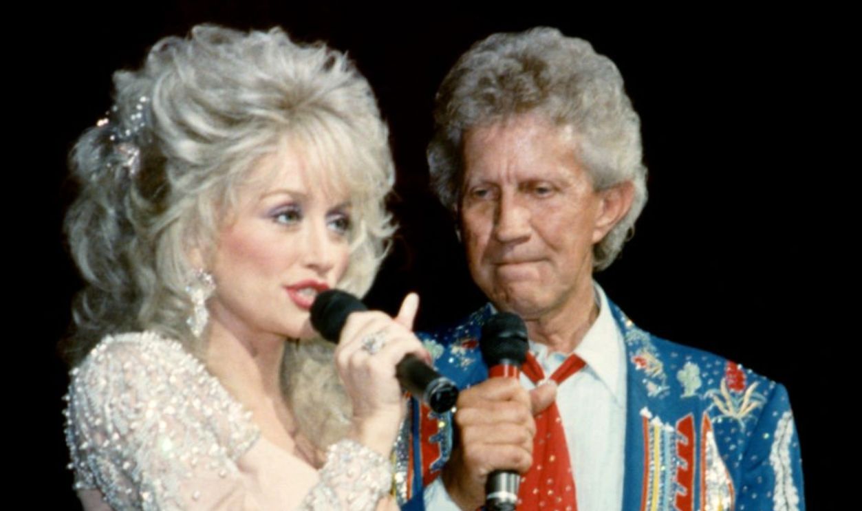 Former duet partners, American singer-songwriter, actress, and businesswoman Dolly Parton and American country music singer Porter Wagoner (1927-2007), sing on stage circa 1990's at the Grand Ole Opry in Nashville, Tennessee.